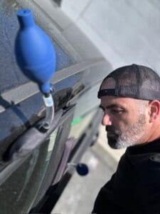 locksmith using air wedge tool to unlock car door during vehicle lockout service