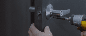 locksmith installing commercial door lock using drill for business security service