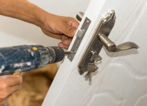 locksmith repairing and installing door lock using drill for home security service