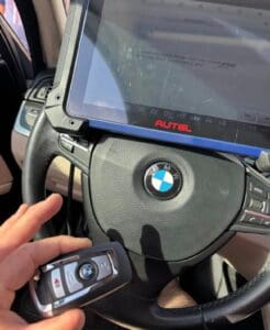 Automotive locksmith programming a BMW smart key fob using Autel diagnostic tool inside a vehicle during key programming service in Anaheim California