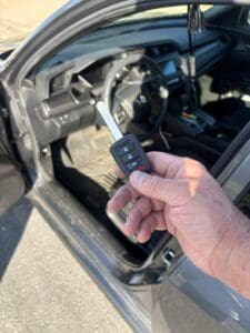 Automotive locksmith holding a car key fob remote inside a vehicle during car key replacement service in Anaheim California